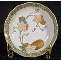 Close-up of an antique hand painted Asian ceramic bowl with floral, green leaf, and orange berry design on metal stand.