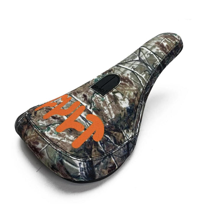 The Cult Tree Camo Slim Pivotal Seat features a camouflage pattern, black stitching, a black center patch, and bold orange side lettering. Made from durable materials and photographed on a white background.