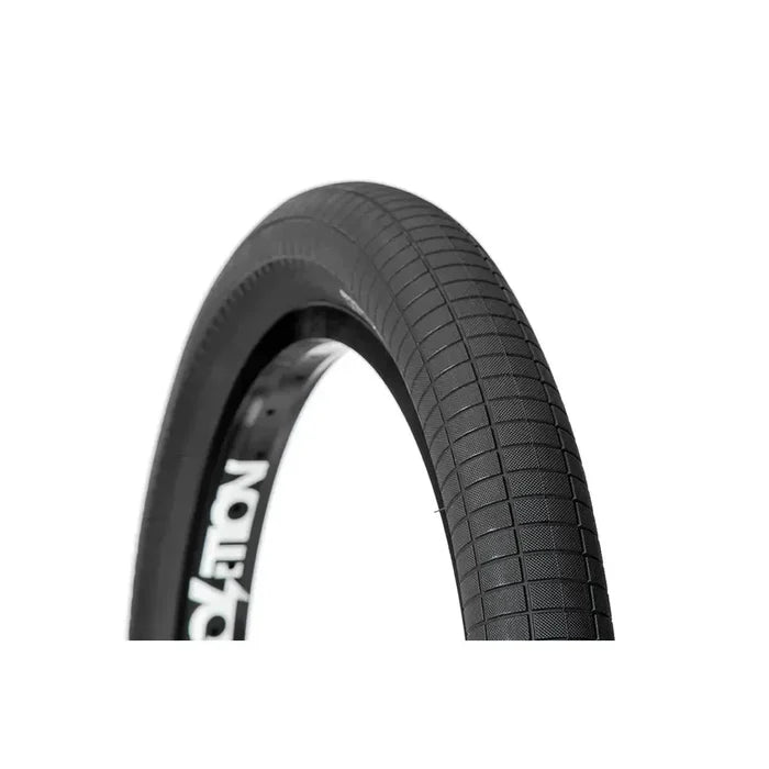 Close-up of a black Demolition HammerHead S 20 Inch Tyre featuring a textured tread pattern, partially mounted on a rim against a white background. This wire bead bicycle tire is offered in both 2.25 and 2.4 inch widths, providing durability and dependable grip for diverse riding conditions.
