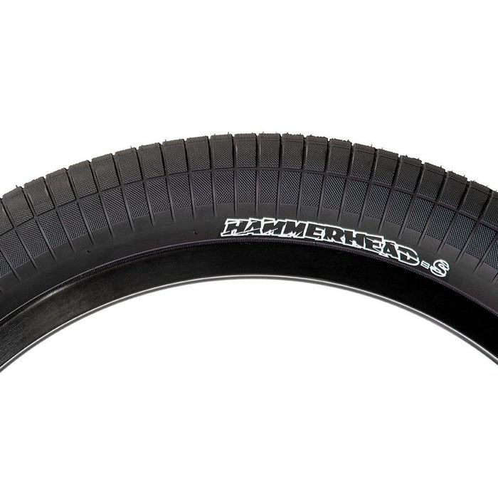 Close-up of a black Demolition HammerHead S 20 Inch Tyre featuring a tread pattern and the label “HAMMERHEAD S” in white lettering on the sidewall. Available in both 2.25 and 2.4 widths, this wire bead tyre ensures reliable grip and performance for various riding styles.