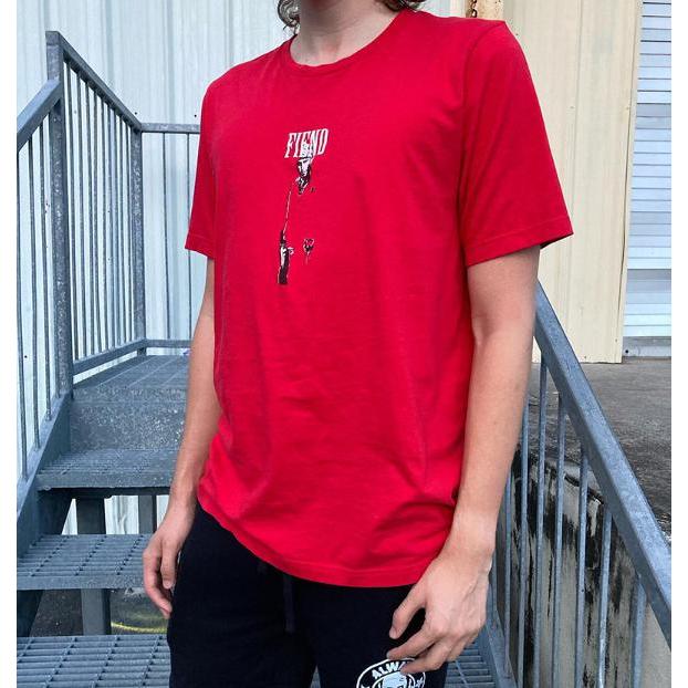 Someone wearing the Fiend Tony Montana Shirt, which features a striking graphic design crafted with discharge printing, stands confidently on a metal staircase.