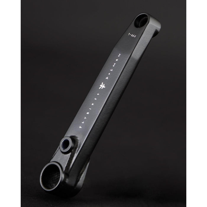 A black Fly Bikes Dolmen 24 crank arm, crafted from CNC machined 4130 Chromoly, is shown on a dark background with white markings and text highlighting its precision and durability.