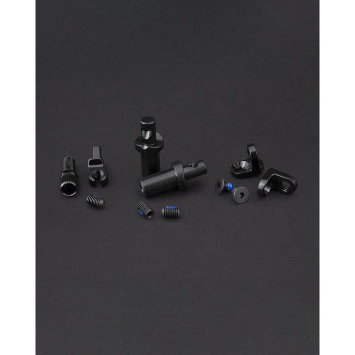 The Fly Bikes EBS Brake Mount Kit features small black mechanical components, including screws, nuts, and cylindrical parts, arranged on a dark surface—essential for any project.