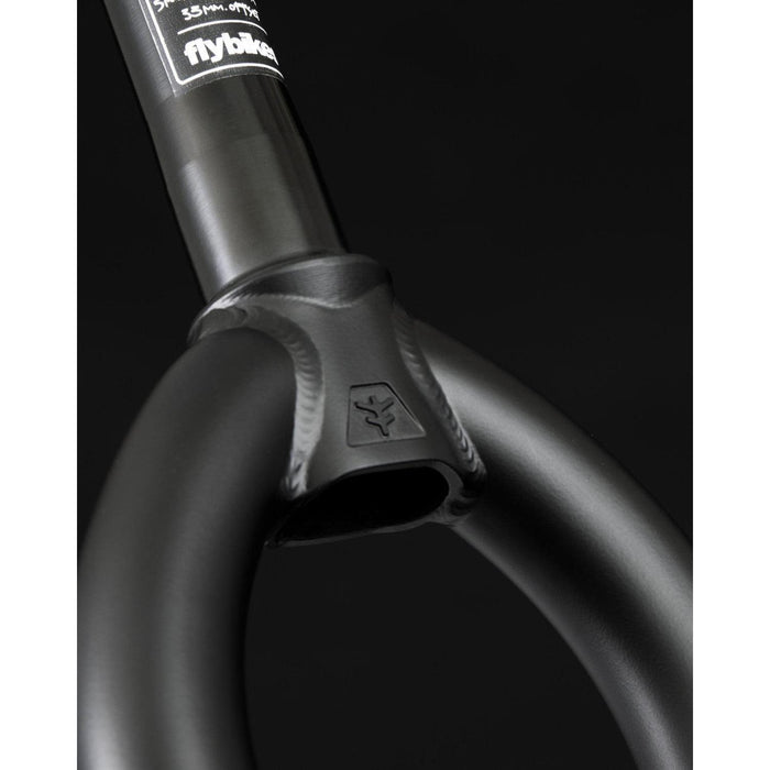 Close-up of Fly Bikes Volcano Forks in black, showcasing a logo, sticker, and matte finish. The BMX fork displays visible welds and excellent tire clearance for smooth rides.