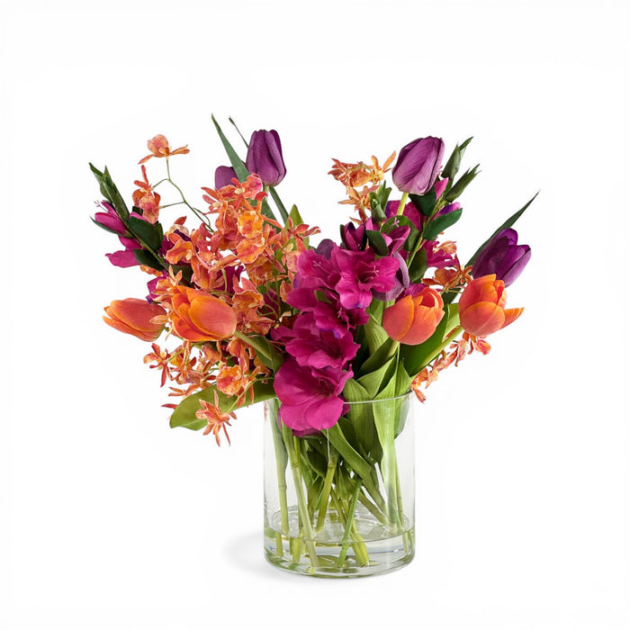 Bouquet of colorful Mixed Faux flowers in a clear vase on a white background