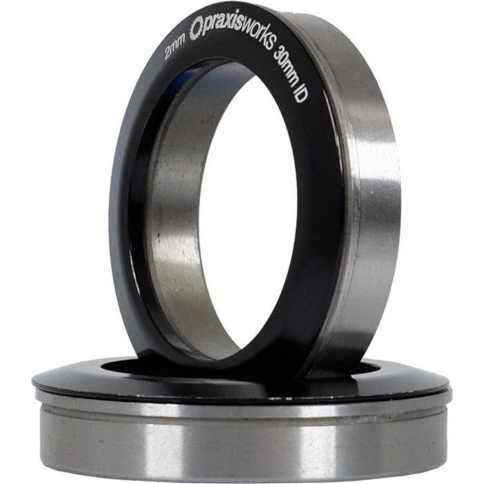 Two metal bearing rings, one upright and one flat, labeled "Praxis Works BB86 30mm THRU Bottom Bracket," designed for BB86 press-fit frames using a 30mm thru spindle.