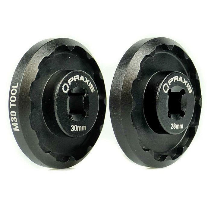 Installing a pair of black wheels using the Praxis Works M30 Standard Bottom Bracket Tool on a white background.