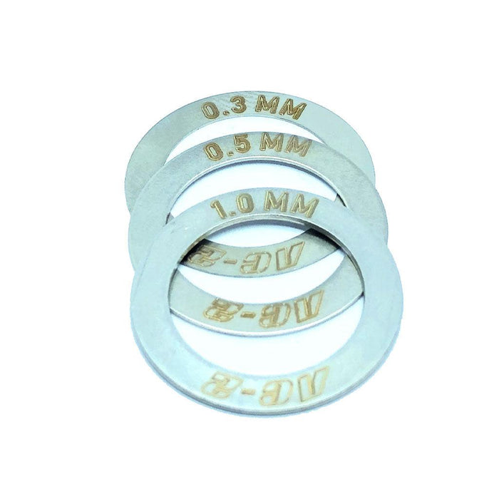 Four metal washers from the PROFILE AC2 HUB SHIM KIT, featuring engraved thickness measurements of 0.3 mm, 0.5 mm, 1.0 mm, and AC-8, are arranged in a slightly overlapping manner.
