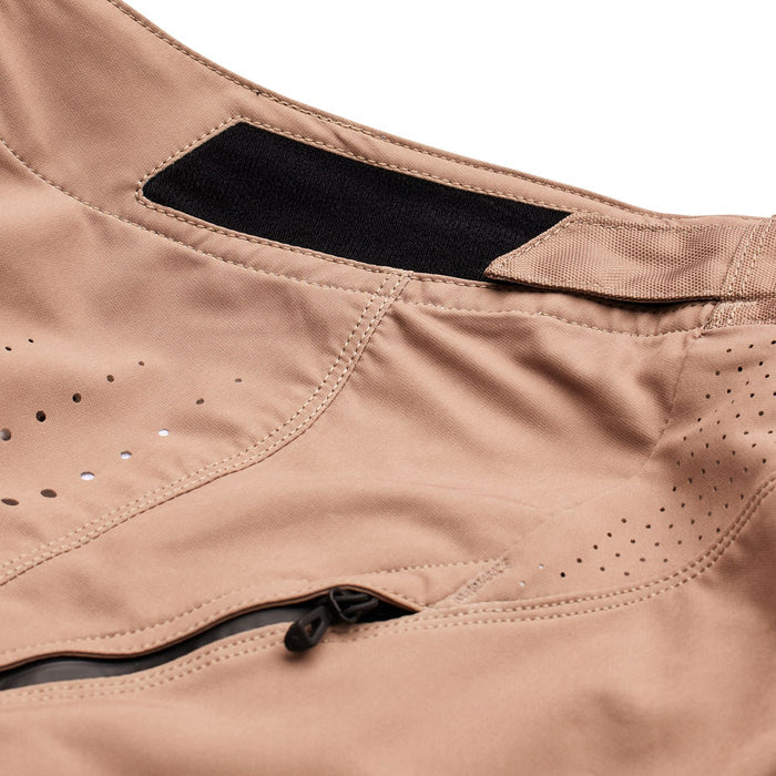 Close-up of the TLD Sprint Pant Mono Oak in tan, inspired by BMX racing, featuring a black velcro waistband adjustment, perforated ventilation holes, and a zippered pocket—perfect for those who want BMX functionality with everyday comfort.