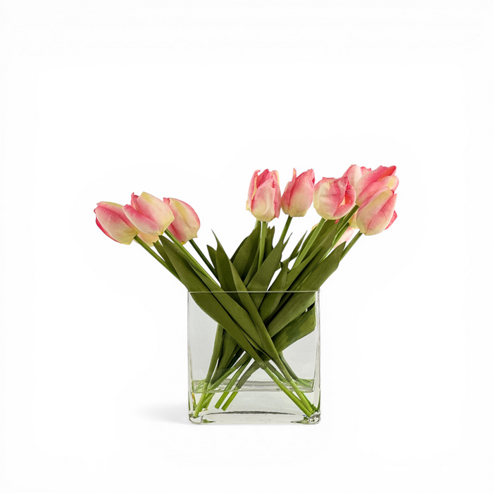 Faux Pink tulips in a clear glass vase on a white background