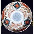 Close-up of a vintage Chinese porcelain plate with red, green, and orange floral and geometric designs on white.